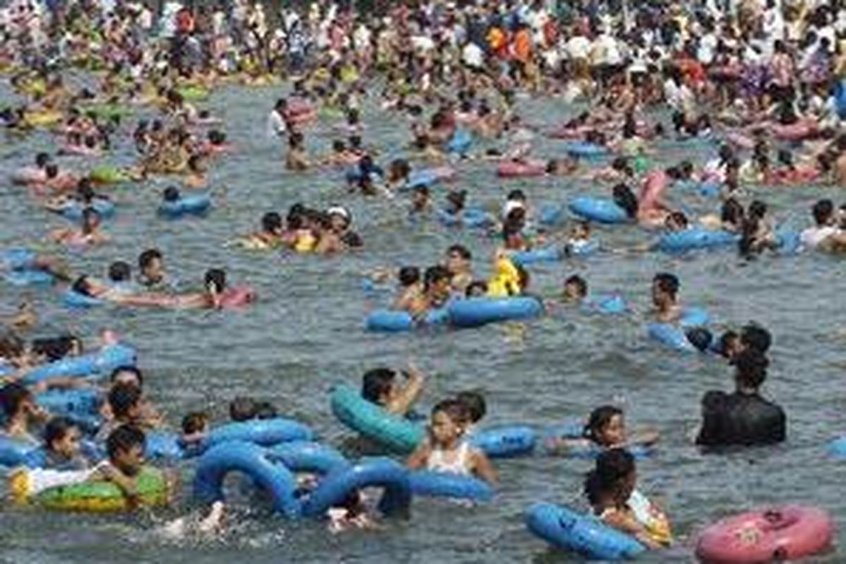 Ratusan warga bermain air di pantai kawasan Taman Impian Jaya Ancol, Jakarta.
