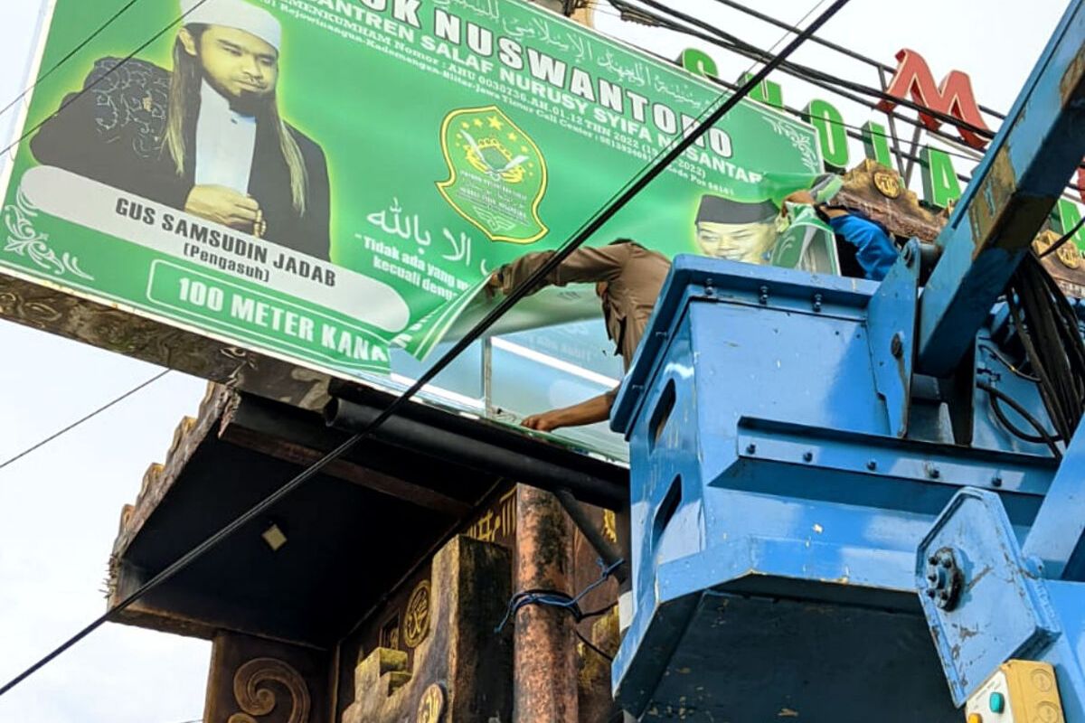 Personel Satpol-PP Kabupaten Blitar menurunkan baliho Samsudin yang terpasang di dekat salah satu padepokan Pondok Pesantren Nuswantoro di Desa Rejowinangun, Kecamatan Kademangan, Kabupaten Blitar, Rabu (6/3/2024)