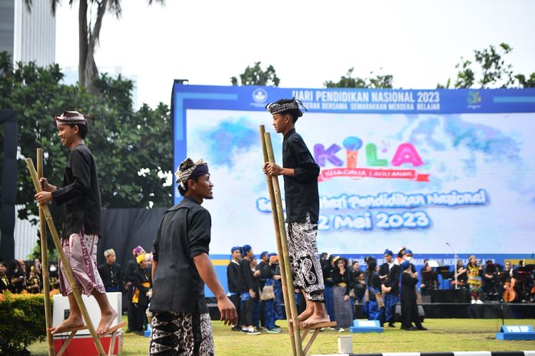 Anak-anak dari Sekolah Adat Pesinauan Osing dari Banyuwangi, Jawa Timur menunjukkan keterampilan bermain egrang batok dan egrang bambu, sebuah permainan tradisional dari suku Osing dalam peringatan Hari Pendidikan Nasional (Hardiknas) 2023 di Kantor Kemendikbud Ristek, Jakarta, Selasa (2/5/2023). 