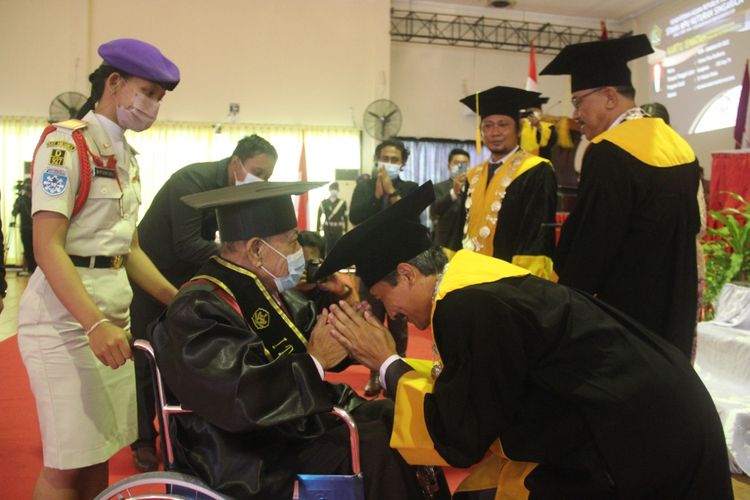 Dewa Putu Budarsa mengikuti prosesi wisuda Sekolah Tinggi Agama Hindu Negeri (STAHN) Mpu Kuturan Singaraja dari atas kursi roda. Dia berhasil meraih gelar sarjana di usia 75 tahun.