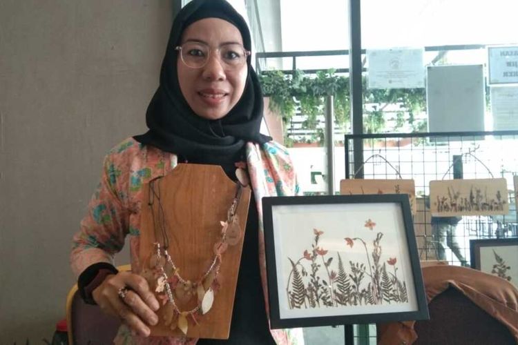 Sanih Supriatin menunjukkan lukisan dan kalung bunga kering dari Buteka buatannya saat mengikuti gelar UMKM di sebuah hotel di Karawang, Jumat (30/12/202).