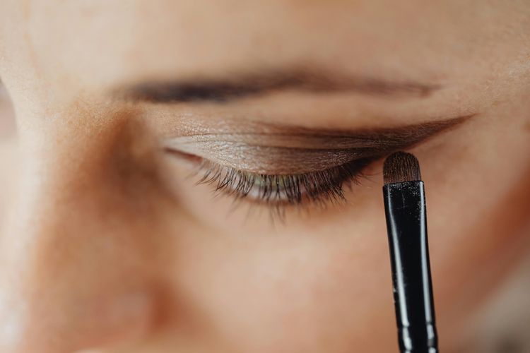Ilustrasi perempuan mengaplikasikan eye makeup pada kelopak mata