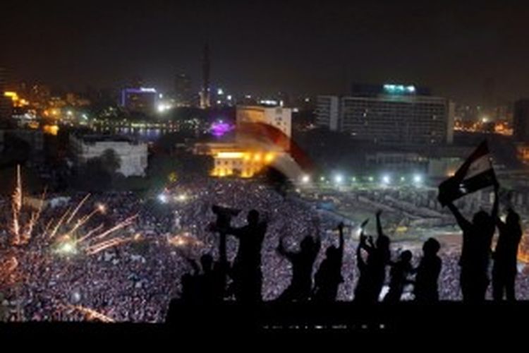 Warga mengibarkan bendera Mesir saat kembang api dilontarkan oleh kubu oposisi yang merayakan kejatuhan Presiden Mesir Muhammad Mursi, di Alun-alun Tahrir, Rabu (3/7/2013). Militer mengambil alih kekuasaan, dengan menyatakan penangguhan konstitusi, menunjuk pemimpin sementara, dan berjanji menjadwalkan segera pemilu Mesir.