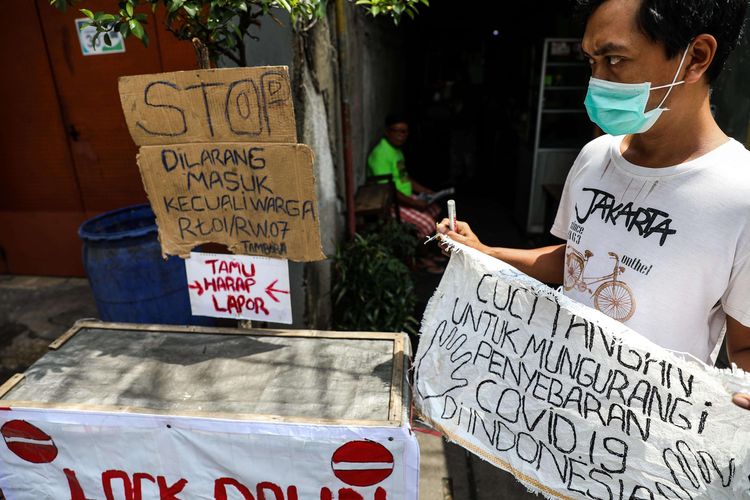 Warga memasang poster berupa himbauan mengenai virus corona di depan gang yang menutup akses jalan di Jalan Tambora RT 01/07, Kelurahan Tambora, Jakarta Barat, Rabu (1/4/2020). Sejumlah kelurahan di Ibu Kota mulai menutup akses jalan untuk mencegah penyebaran virus corona atau  COVID-19.