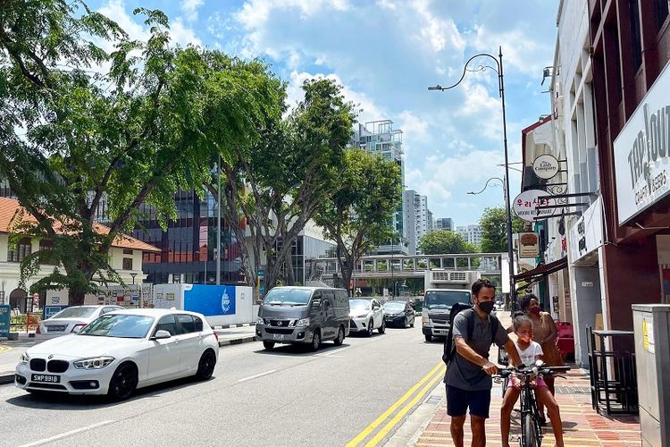 Ekspatriat asing yang memakai masker terlihat sedang melintas dengan sepedanya di trotoar Jalan East Coast, distrik Tanjong Katong, Singapura Timur, Sabtu siang (29/1/2022)