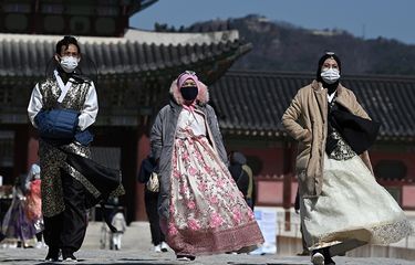 Orang-orang dengan pakaian tradisional Korea mengenakan masker wajah saat mengunjungi Istana Gyeongbokgung di Seoul, Korea Selatan, menyusul meluasnya wabah virus corona di negara itu, Minggu (23/2/2020). Penyebaran virus corona hingga hari ini, Senin (24/2/2020), semakin menunjukkan peningkatan di sejumlah negara, seperti Italia, Iran, dan Korea Selatan.
