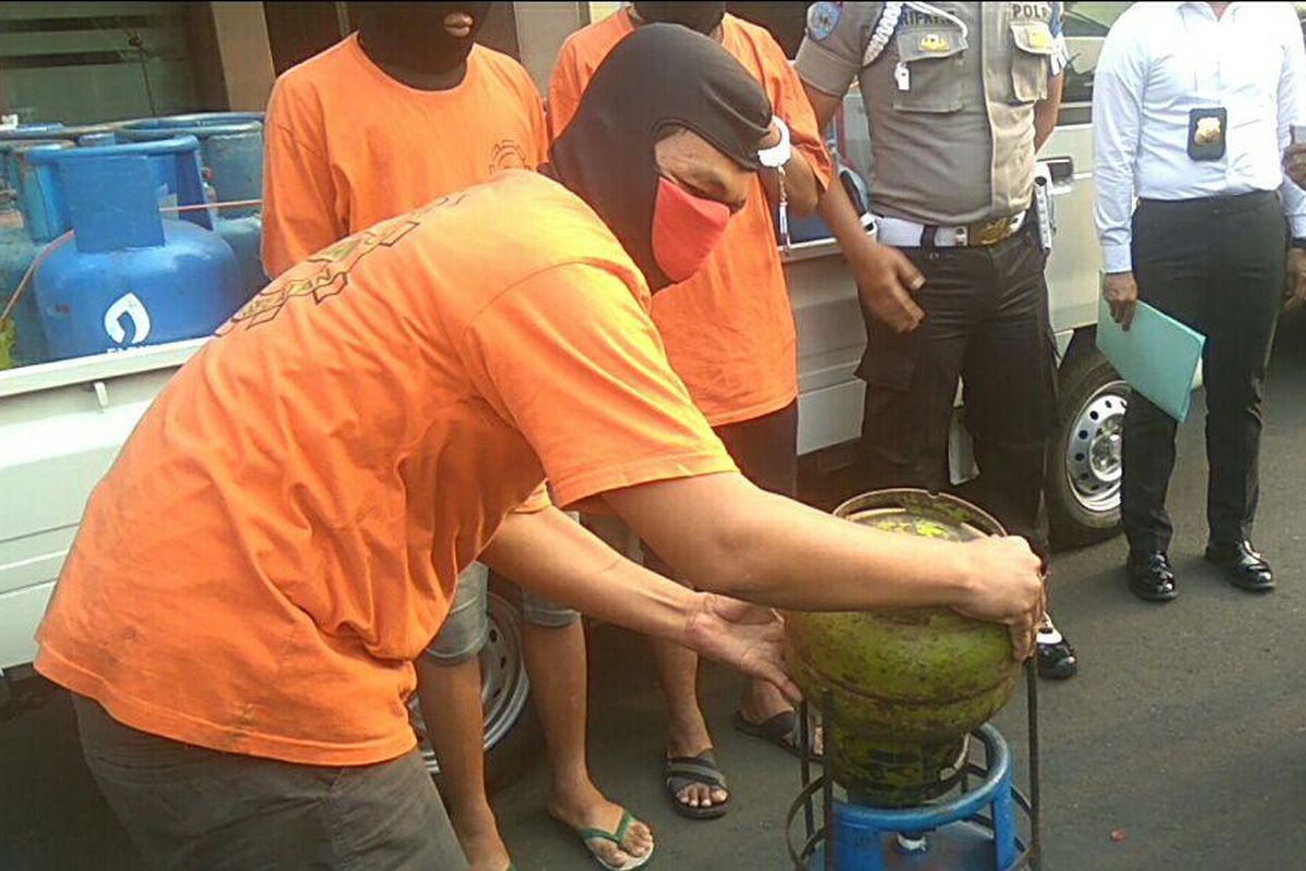 Tersangka komplotan pengoplos gas memeragakan cara menyuntikkan isi tabung gas 3 kilogram ke tabung gas 12 kilogram di Mapolrestro Jakarta Selatan, Rabu (20/9/2017).