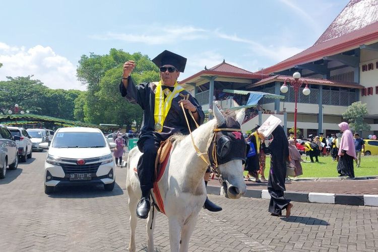 Endra Harsaya (60) atau lebih dikenal Hendro Plered saat naik kuda usai usai diwisuda di UGM. Hendro naik kuda keliling Grha Sabha Pramana UGM.