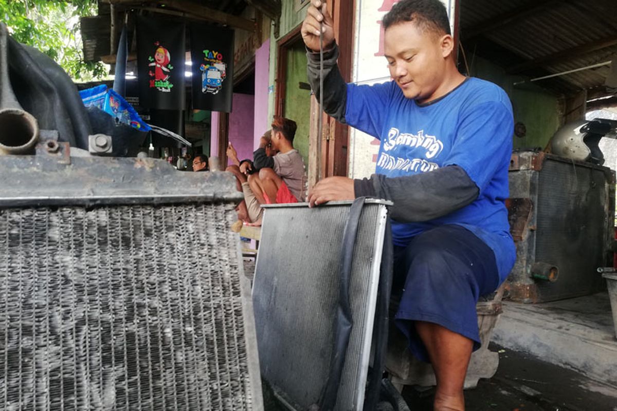 seorang teknisi spesialis radiator tengah melakukan perbaikan radiator salah satu pelanggannya.