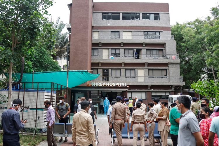 Petugas polisi dan kerabat berdiri di luar rumah sakit tempat kebakaran terjadi di dalam Unit Perawatan Intensif (ICU) yang merawat pasien yang terinfeksi penyakit virus corona (Covid-19) di Ahmedabad, India, 6 Agustus 2020.