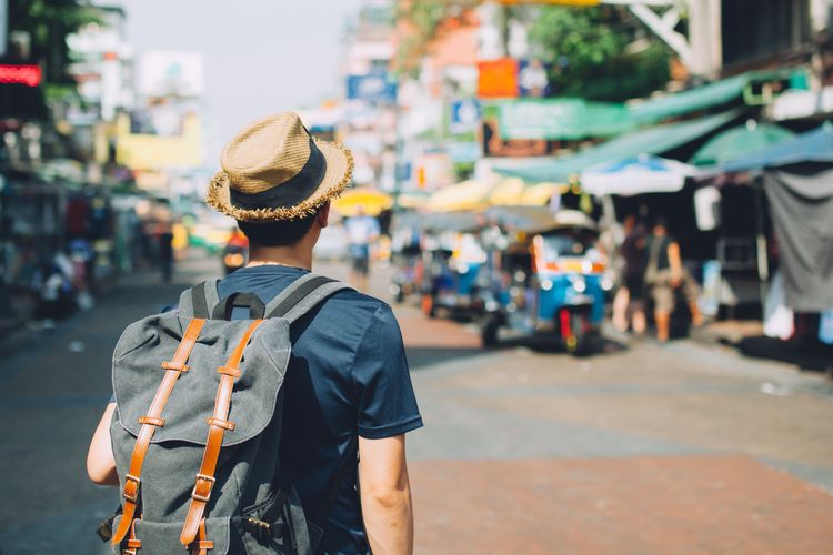 Young Asian traveling backpacker in Khaosan Road outdoor market in Bangkok, Thailand 