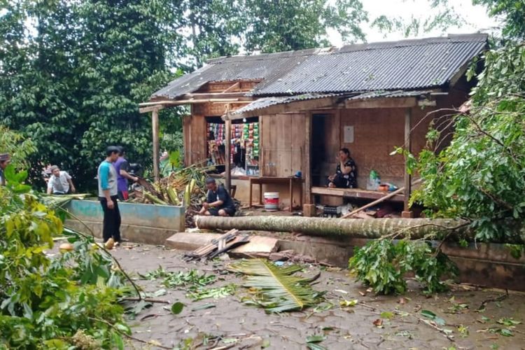 Sejumlah petugas sedang membersihkan pohon dari atap bangunan rumah yang tertimpa dalam bencana angin puting beliung di Cianjur Jawa Barat, Minggu (26/12/2021)
