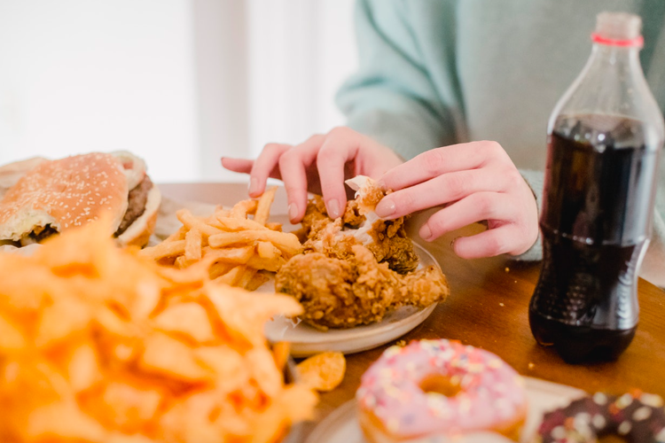Ilustrasi makan makanan tinggi lemak dan kalori. Kebiasaan makan makanan tinggi kalori, tinggi lemak, dan rendah serat adalah faktor risiko kanker usus besar. 