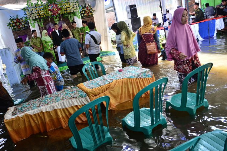 Pasangan Abdul Lathif Anshori dan Elok Faiz Fatma Elfahmi, melangsungkan resepsi pernikahan di tengah kepungan banjir, Rabu (1/5/2019). 