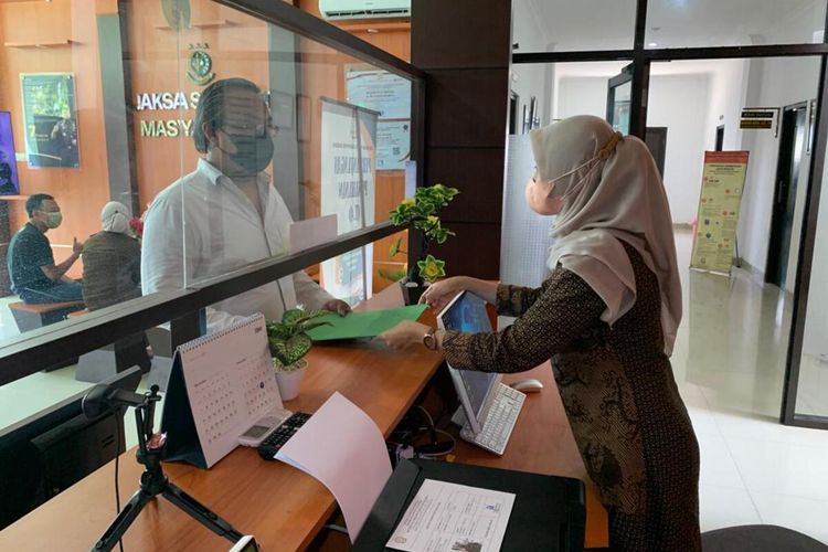 LAPORKAN—Koordinator Petir, Rizal Simanjuntak memasukkan laporan pengaduaan dugaan korupsi pada kasus pemungutan biaya pemakaman jenazah covid-19 di Desa Purworejo, Kecamatan Pilangkenceng di Kejaksaan Negeri Kabupaten Madiun, Kamis (9/12/2021).