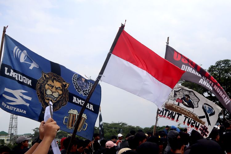 Suporter Arema, Aremania membentangkan bendera saat melakukan aksi damai Tragedi Kanjuruhan menuntut keadilan yang dilaksanakan di 18 titik Kota Malang, Minggu (20/11/2022) siang.