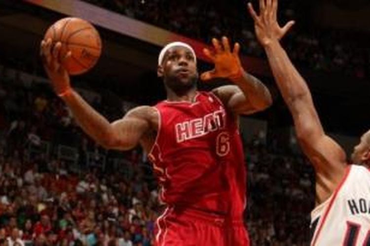 Forward Miami Heat, LeBron James hendak mengoper bola di bawah penjagaan pemain Atlanta Hawks, Al Horford, pada pertandingan lanjutan NBA 2013-2014, di American Airlines Arena, Senin (23/12/2013).