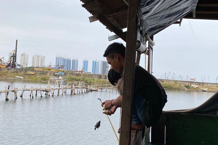 Rumah apung yang berada di pinggir Teluk Jakarta dihuni ratusan warga. Beberapa warga terlihat memancing ikan dari teras rumahnya, Jumat (27/1/2023). 