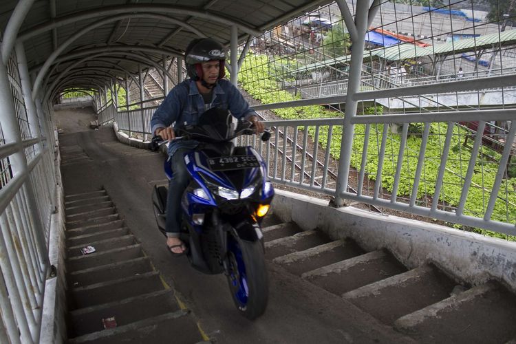 Pengendara sepeda motor melintasi jembatan penyebrangan orang (JPO) di dekat Stasiun Pasar Minggu Baru, Pasar Minggu, Jakarta Selatan, Minggu, (15/12/2019). Para pejalan kaki kerap harus mengalah dengan pengendara motor yang melintasi JPO.