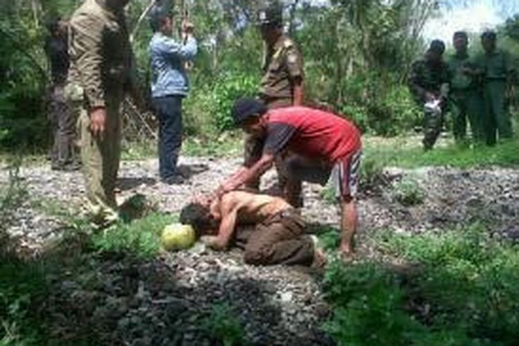 Suseno (berkaus merah) menggagalkan upaya Sukirman (tertelungkup) menghabisi nyawa sendiri dengan minum obat penyemprot rumput di tempat pemakaman umum Gogoh Deso, Kecamatan Kanigoro, Kabupaten Blitar, Senin (4/11/2013).