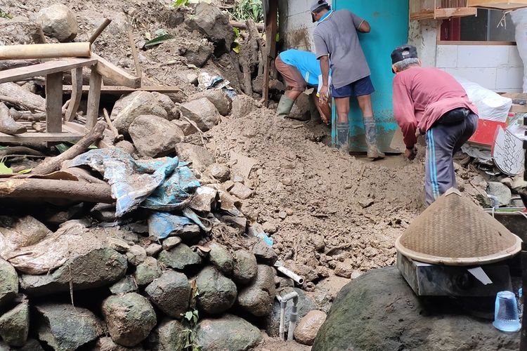 Warga gotong royong membantu membersihkan material longsor yang menerpa satu sisi dapur rumah milik Parjo pada Pedukuhan Krikil, Kalurahan Pendoworejo, Kapanewon Girimulyo, Kabupaten Kulon Progo, Daerah Istimewa Yogyakarta.