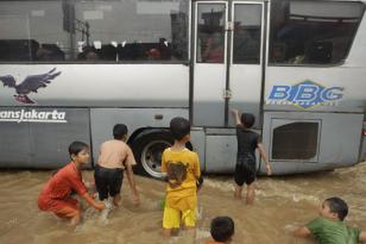 Anak-anak bermain di tengah banjir yang menggenangi Jalan Otista, Bidara Cina, Jakarta, Senin (13/1/2014). Hujan yang melanda Jakarta sejak Minggu pagi ditambah meluapnya sungai Ciliwung akibat banjir kiriman dari Bogor mengakibatkan sejumlah kawasan ini terendam banjir sejak Minggu malam. KOMPAS IMAGES/RODERICK ADRIAN MOZES