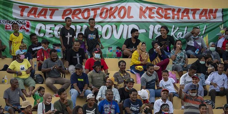 Warga menyaksikan pertandingan babak enam besar sepak bola putra PON XX Papua 2021 antara Tim Papua melawan Tim Aceh di Stadion Mandala, Kota Jayapura, Papua, Rabu (6/10/2021). Sejumlah laporan dari PON XX Papua menunjukkan sebagian penonton yang hadir di venue pertandingan ditemukan masih lalai terhadap protokol kesehatan, seperti tidak mengenakan masker dan mengabaikan pembatasan jarak.