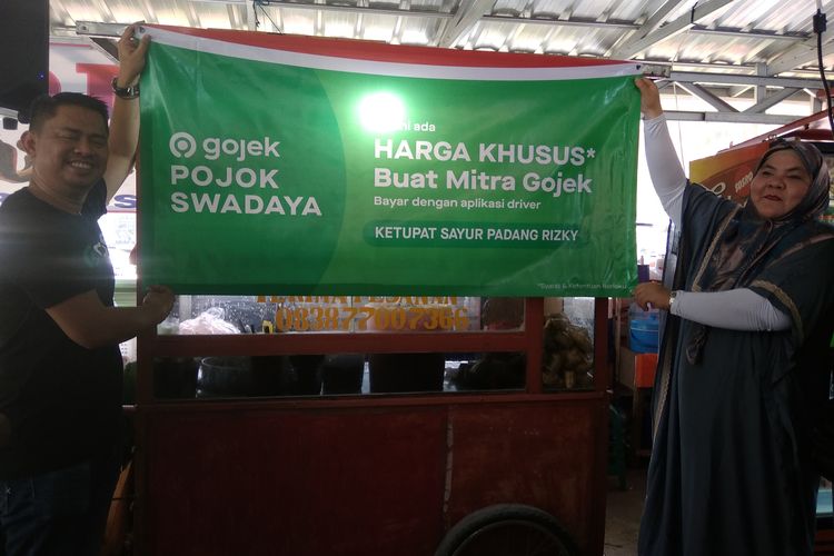 Gede Manggala, VP of Operations Jabodetabek Gojek memberikan banner pojok Swadaya kepada Fitri Merchant Tupat Sayur Padang Risky, di Jakarta, Selasa (13/11/2019).