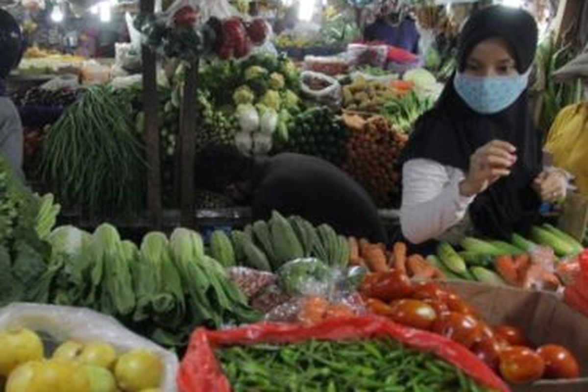 Warga dengan masker memilih sayuran di pasar tradisional Pondok Labu, Jakarta, Minggu (07/06). 