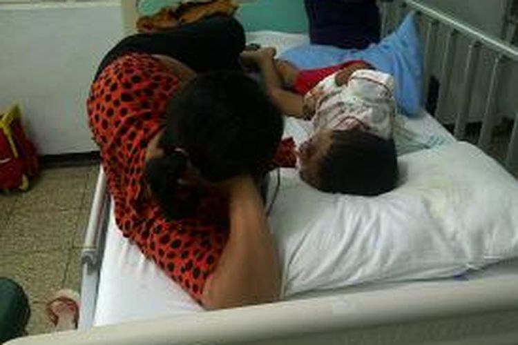 Bocah 7 tahun penderita tumor mata, Sandi Septiono saat ditenangkan oleh ibunya karena terus menangis menahan sakit di bagian mata dan kepala. Sandi dirawat di ruang perawatan anak lantai 2 RSUP Dr Kariadi Semarang, Jumat (4/10/2013)