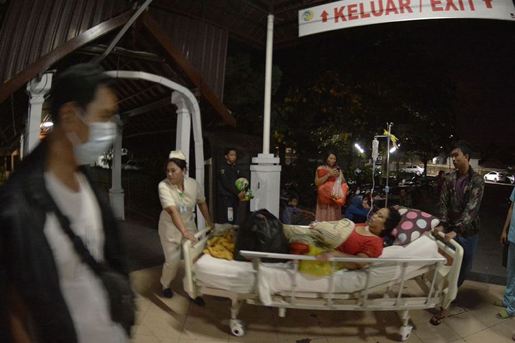 Petugas medis memindahkan pasien dari ruang perawatan ke luar ruangan usai terjadi gempa di RSUP Sanglah, Denpasar, Bali, Minggu (19/8/2018). Sejumlah pasien di rumah sakit tersebut dipindahkan ke tenda dan lorong rumah sakit pascagempa bermagnitudo 7 yang berpusat di Lombok Timur pada Minggu malam.