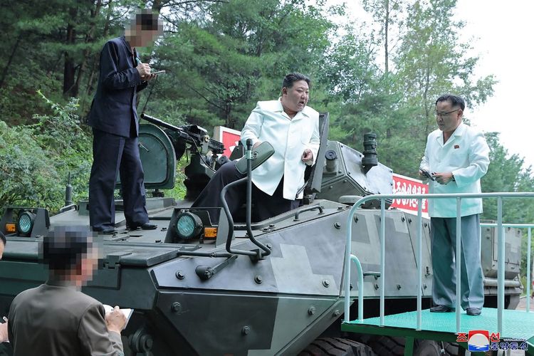 Foto tak bertanggal yang dirilis dari Kantor Berita Pusat Korea Utara (KCNA) pada 14 Agustus 2023 ini menunjukkan pemimpin Korea Utara Kim Jong Un (tengah) berada di atas kendaraan lapis baja serbaguna setelah kunjungan ke pabrik amunisi penting di lokasi yang dirahasiakan di Korea Utara. 