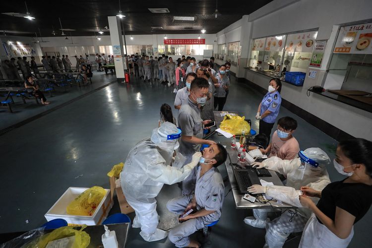 A worker receives a nucleic acid test for the Covid-19 coronavirus at the dining hall of a car parts factory in Wuhan, in China's central Hubei province on August 4, 2021. (Photo by STR / AFP) / China OUT