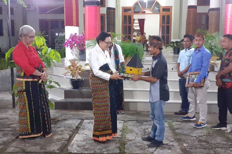 Komunitas milenial Boleng di Kecamatan Boleng menyerahkan cendramata kepada Ibu Wakil Bupati Manggarai Barat, Ibu Maria Geong saat misa syukur berupa rumah adat Manggarai Raya dengan bahan koran bekas, Kamis, (27/2/2020). (KOMPAS.com/MARKUS MAKUR)