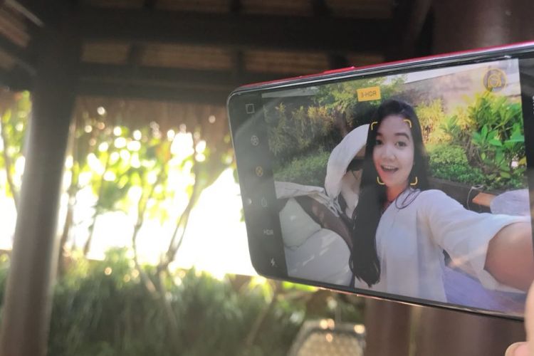 Seorang perempuan berselfie menggunakan kamera depan Oppo F7.