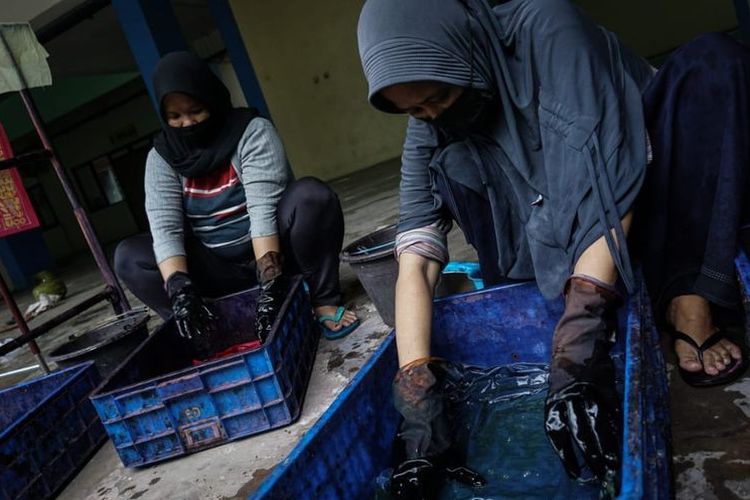 Ibu-ibu perajin batik tulis Rusun Pulogebang sedang mewarnai kain batik yang telah mereka lukis dengan canting, Jumat (18/6/2021)