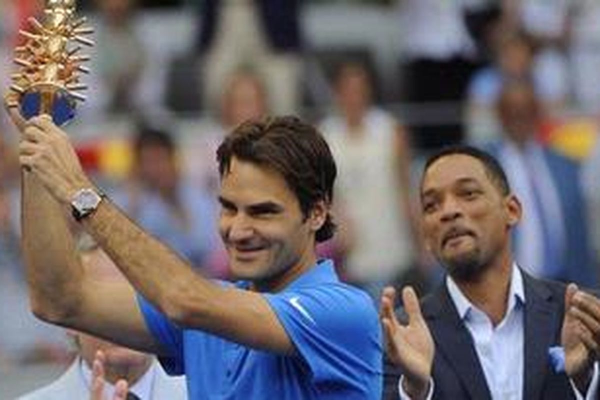 Petenis Swiss, Roger Federer, mengangkat trofi Madrid Masters yang direngkuh usai kalahkan Tomas Berdych, Minggu (13/5/2012).