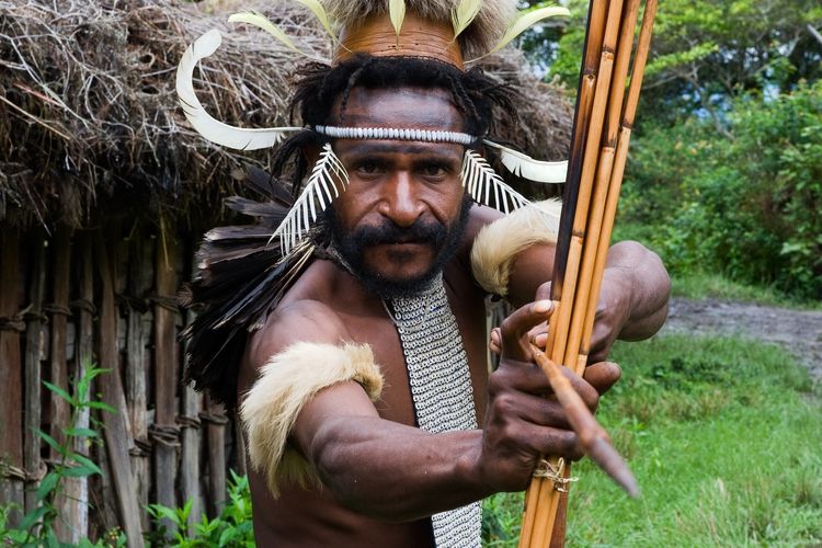 CENTRAL PAPUA, NEW GUINEA - JUNE 25: The warriorr of Dani Dugum tribe with an bow and an arrow aims in the photographer. Indonesia. Papua New Guinea. Village of people Dani Dugum. June 25, 2009.