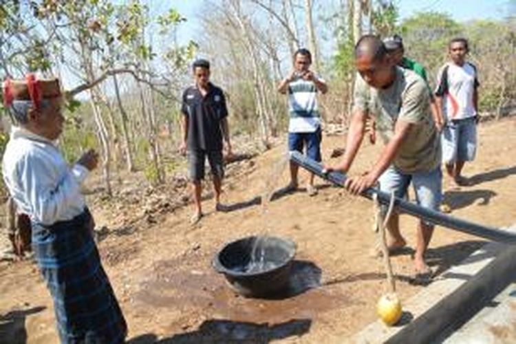 Tokoh adat Kampung Sambikoe, Kelurahan Watu Nggene, Kecamatan Kota Komba, Manggarai Timur, Flores, NTT, Senin (14/9/2015), Angelus Enggong, sekaligus Orang Pintar (Api Pandu) sedang melaksanakan ritual Sundung Wae (Jemput air) yang masuk di Bak Penampung Utama di kampung tersebut. Dia memegang sebutir telur ayam kampung dan kelapa muda sebagai persembahan kepada alam dan leluhur. (Kompas.com/Markus Makur)