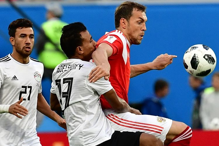 Artem Dzyuba mencoba lepas dari pengawalan Mohamed Abdel-Shafy pada pertandingan Rusia vs Mesir di St. Petersburg, 19 Juni 2018. 