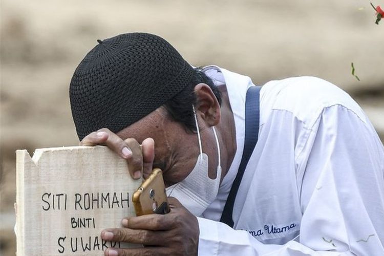 Warga menangis di atas nisan keluarganya di area pemakaman khusus COVID-19 di TPU Rorotan, Cilincing, Jakarta Utara, Senin (28/6/2021).
