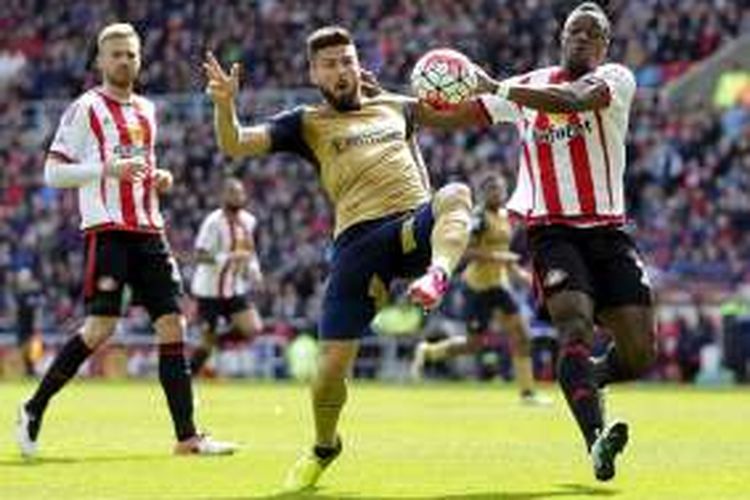 Penyerang Arsenal, Olivier Giroud (kiri), berduel dengan bek Sunderland, Lamine Kone, dalam lanjutan Premier League di Stadium of Light, Minggu (24/4/2016).