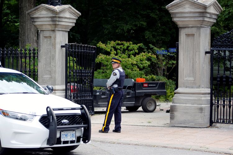 Seorang polisi berjaga di dekat pagar Rideau Hall yang rusak. Kompleks tersebut adalah lokasi kediaman resmi Perdana Menteri Kanada Justin Trudeau. Kediamannya sempat disusupi tentara bersenjata ilegal pada Kamis (2/7/2020).