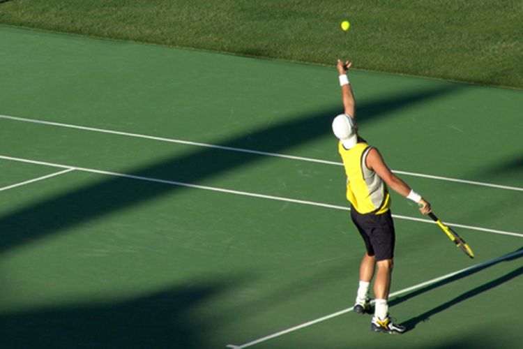 Seorang atlet tenis profesional sedang menservis bola.