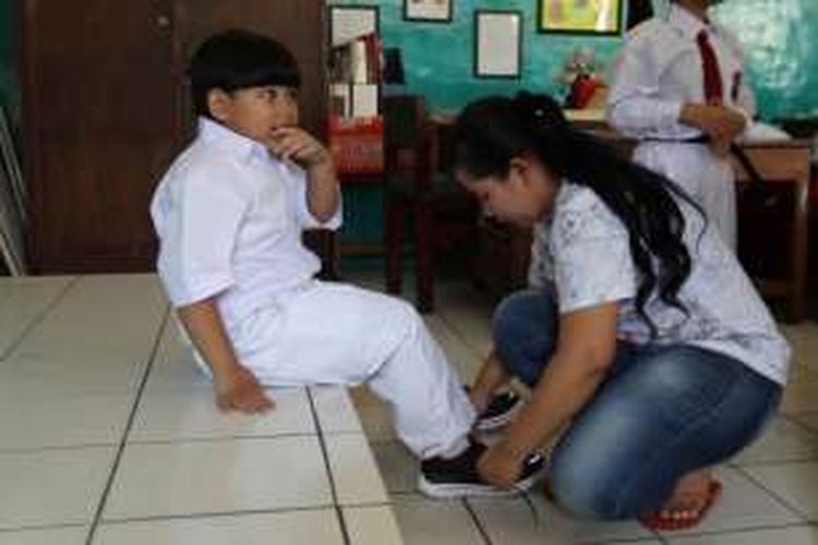 Orangtua murid baru kelas I memasangkan sepatau saat hari pertama masuk sekolah, di Sekolah Dasar Negeri Palmerah 07 Pagi, Palmerah Utara, Jakarta, Senin (18/7/2016). Sebanyak 65 murid baru di SDN Palmerah 07 Pagi nampak diantar oleh orangtua pada hari pertama tahun ajaran baru 2016/2017.

