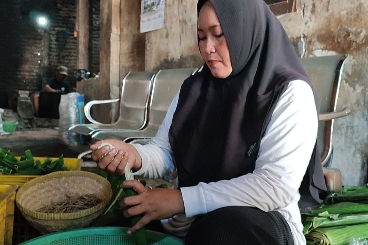 Nurlaela (42), Nurlaeli , dan Yani (62), pembuat lontong di Jalan Kandang Perahu, Kelurahan Karyamulya Kecamatan Kesambi Kota Cirebon Jawa Barat memasukan beras ke dalam daun pisang wadah lontong, di rumahnya, Kamis (22/2/2024) petang.