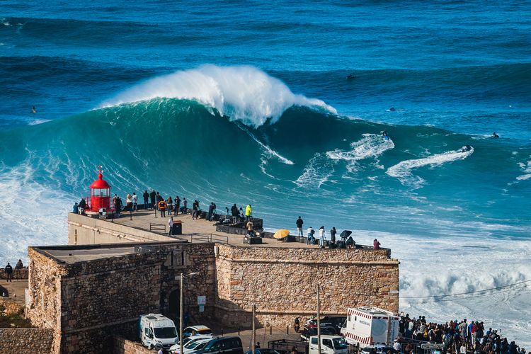 Peselancar mencoba menaklukkan ombak raksasa dekat Benteng Mercusuar Nazare di Nazare, Portugal. Nazare terkenal di kalangan peselancar karena memiliki ombak-ombak terbesar di dunia.