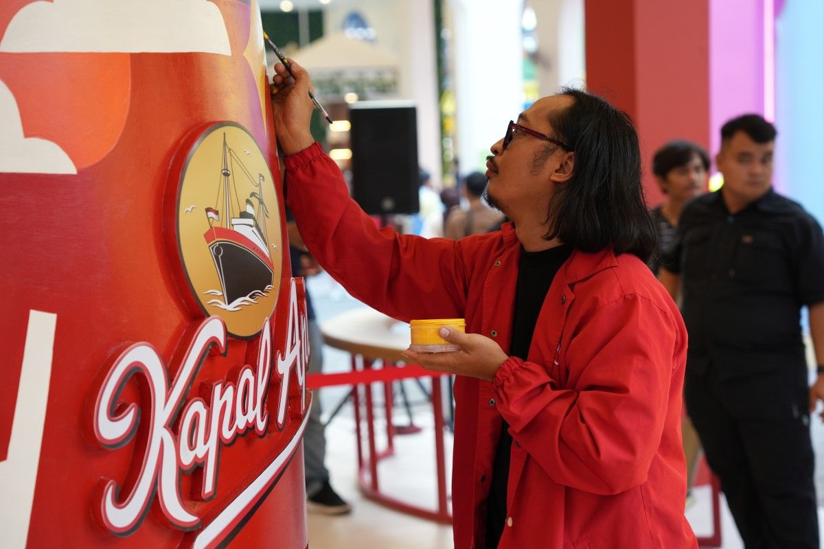 Popomangun saat memberi sentuhan akhir untuk lukisan pada media tumbler raksasa yang terpajang di booth Kapal Api.