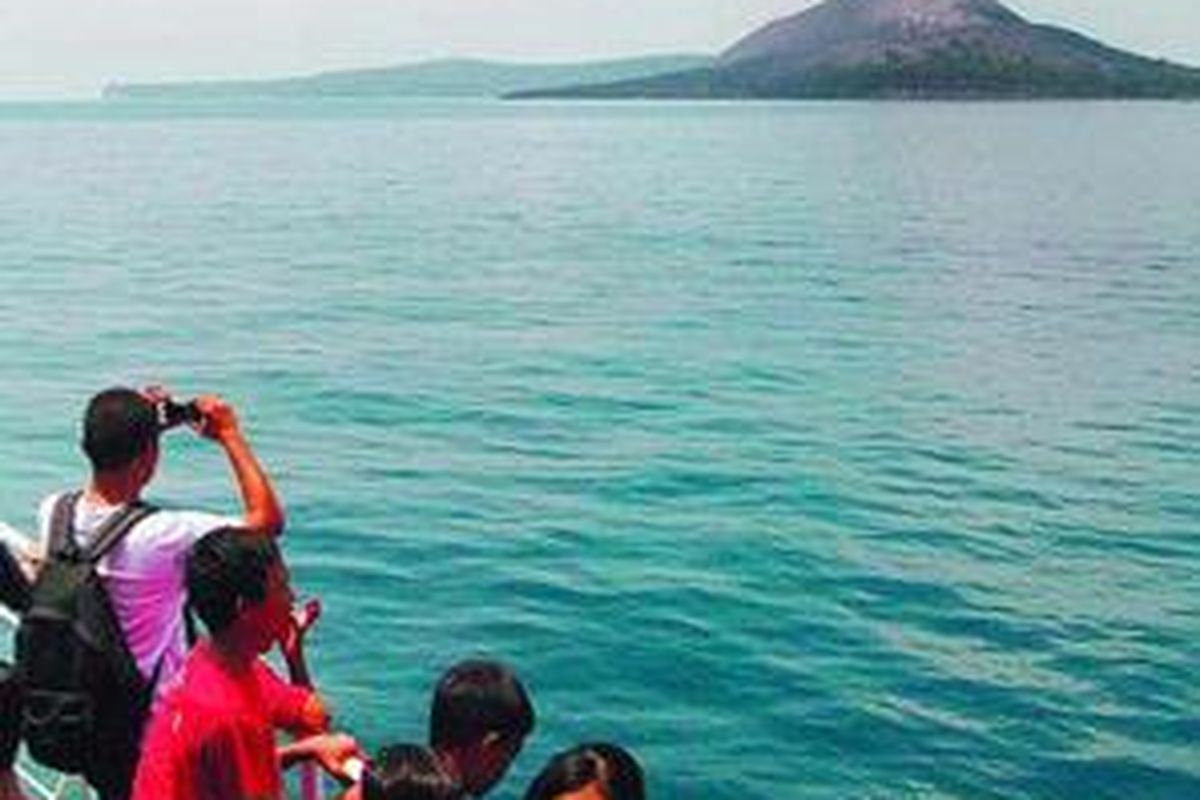 Wisatawan tengah melihat dan mengabadikan pemandangan Kepulauan Krakatau dari geladak Kapal Motor Penumpang Jatra III, di perairan Selat Sunda, Sabtu (15/11). 