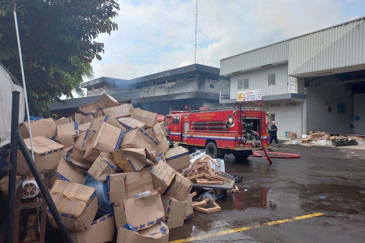 Pegawai menyelamatkan paket milik pelanggan dari kebakaran yang melanda Gudang JNE, Senin (12/9/2022). Kardus-kardus tersebut ditumpuk di gerbang masuk. 